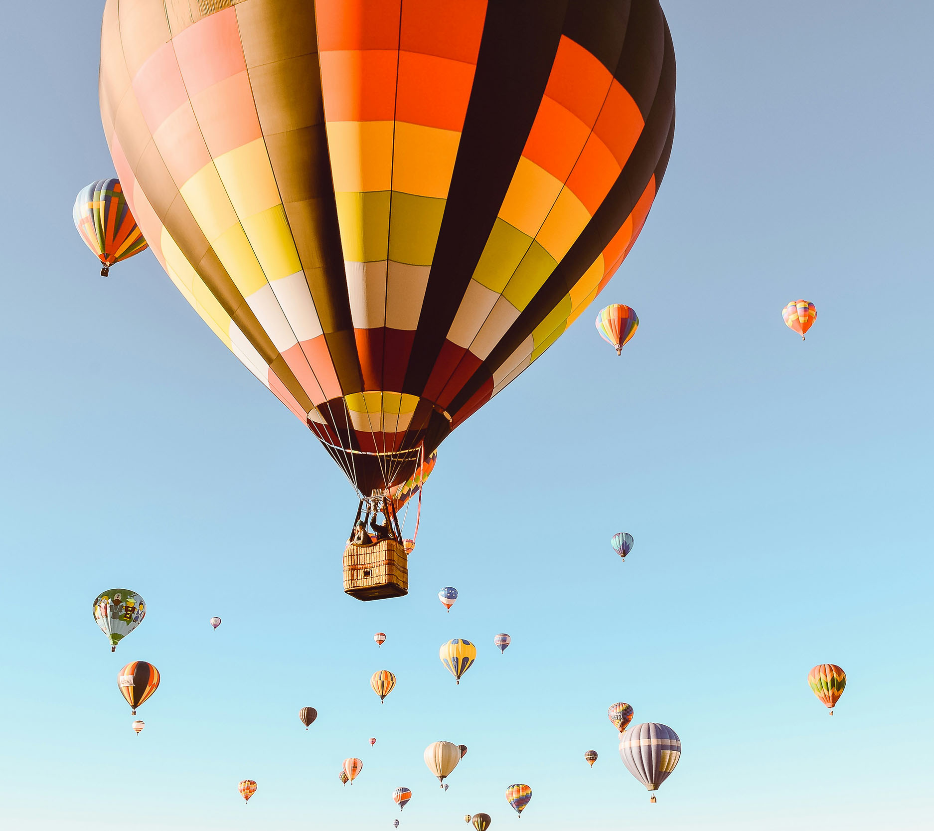 over a dozen hot air balloons in a cloudless blue sky with one hot air balloon in the foreground bigger than the others, Sheaff Brock investment advisors blog, retail consumers