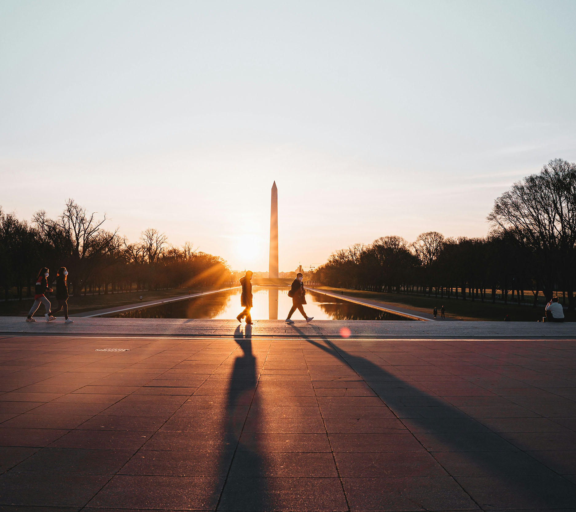 Sheaff Brock market update newsletters, October 2024, the Washington Monument and reflecting pool at sunrise with two people's silhouettes walking in front of the pool